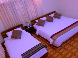 two beds in a room with white sheets at Inle Star Hotel in Nyaungshwe Township +50 photos
