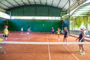 a group of people playing tennis on a tennis court at Bomtempo Itaipava by Castelo Itaipava in Itaipava