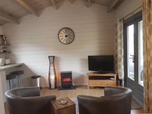 a living room with a fireplace and a clock on the wall at CROFTERS CABIN in Bracadale