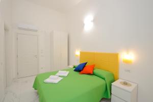 um quarto com uma cama verde e almofadas coloridas em B&B Valentì em Amalfi