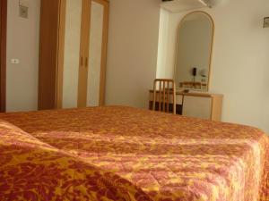 Schlafzimmer mit einem Bett, einem Spiegel und einem Tisch in der Unterkunft Hotel Apis in Rimini