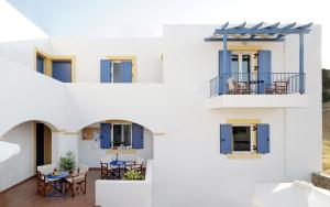 a white building with blue shutters and a table on a balcony at Kythera Golden Sun in Agia Pelagia