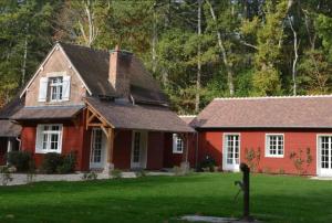 a red house with white windows in a yard at Maison canadienne in Salbris