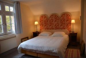 a bedroom with a large bed with a large headboard at Maison canadienne in Salbris +11 photos