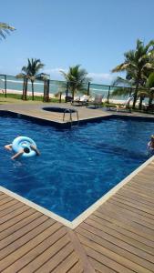 a swimming pool with a person in the water at Condomínio Summer House, Itacimirim in Itacimirim