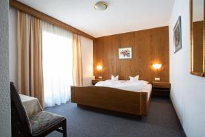ナウダースにあるPension Tirolのベッドと椅子付きのホテルルーム