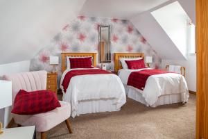 a attic bedroom with two beds and a chair at Ceol na Mara Guest House in Tarbert