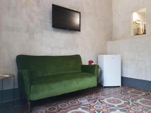 un sofá verde en una sala de estar con TV en I Lumi, en Catania