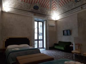 1 dormitorio con 2 camas, sofá y TV en I Lumi, en Catania