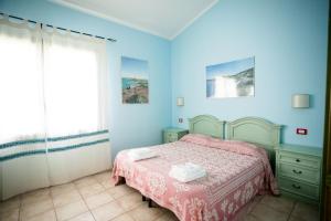 a blue bedroom with a bed and a window at Agriturismo Archelao in Oristano