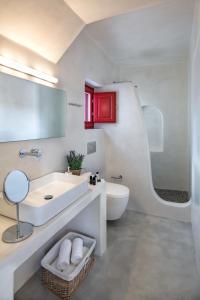 uma casa de banho branca com um lavatório e um WC em Aplada Suites em Oia