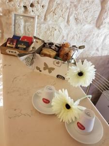 un tavolo con due piatti bianchi e fiori di Alloggio Turistico Suite Nino a Ceglie Messapica