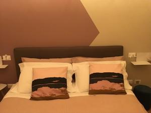 un letto con cuscini bianchi e testiera marrone di Hotel Moniga a Desenzano del Garda