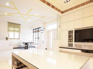 a living room with a large white kitchen with a flat screen tv at Yilan NAI-JI House in Dongshan
