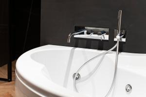 a white bath tub with a shower in a bathroom at Artemide Guest House in Florence