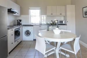 a kitchen with a white table and white chairs at De Zalze Winelands Golf Lodge 6 in Stellenbosch
