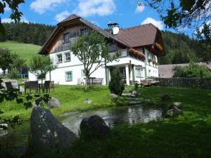 ein Haus mit einem Teich davor in der Unterkunft Dorfergut in Weisspriach