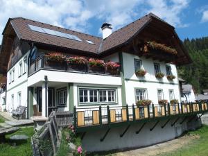 een wit huis met bloembakken op het balkon bij Dorfergut in Weisspriach