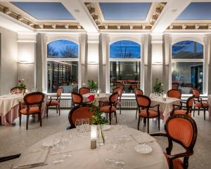 a dining room with tables and chairs and windows at Hotel Metropole Suisse in Como