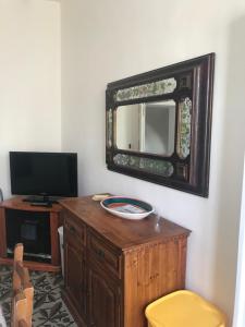 a mirror on a wall next to a desk with a yellow stool at Casa Cardi in Sperlonga