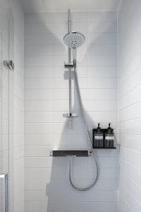 a shower in a white tiled bathroom at Zoku Amsterdam in Amsterdam