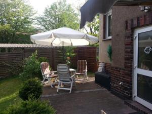 eine Terrasse mit einem Tisch, Stühlen und einem Sonnenschirm in der Unterkunft Ferienwohnung Spandau in Berlin