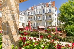 a large white building with flowers in front of it at HOTEL am STRAND in Kühlungsborn