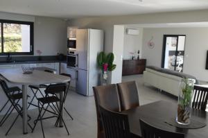 eine Küche und ein Wohnzimmer mit einem Tisch und einem Kühlschrank in der Unterkunft Villa au coeur du Gers avec vue sur les Pyrénées in Caumont
