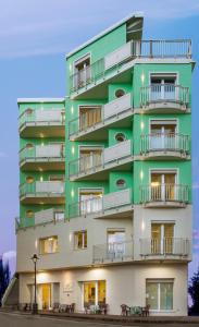 - un bâtiment avec des balcons et des tables en face dans l'établissement Beach Residence, à Gabicce Mare