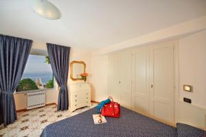 a bedroom with a bed with a red suitcase and a window at Le Querce Resort Sea Thermae & Spa in Ischia