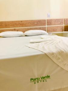 Una cama con dos almohadas encima. en Porto Verde Hotel, en Lins