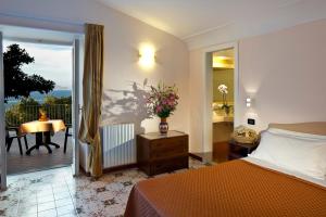 a bedroom with a bed and a balcony with a table at Le Querce Resort Sea Thermae & Spa in Ischia
