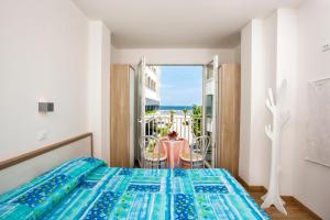 a bedroom with a bed and a balcony with a table at Beach Residence in Gabicce Mare