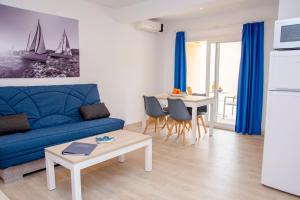 un soggiorno con divano blu e tavolo di Apartamentos Maribel a Cala Blanca