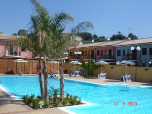 a swimming pool with palm trees and umbrellas at Case Vacanze Ancora in Porto Empedocle