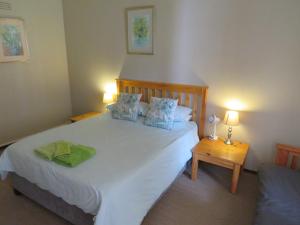 a bedroom with a large white bed with two lamps at Haus Victoria Self Catering Cottages in Oudtshoorn