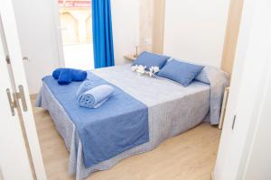 a bedroom with a bed with blue sheets and blue pillows at Apartamentos Maribel in Cala Blanca