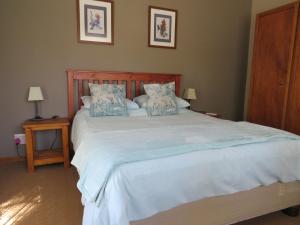 a bedroom with a large white bed with blue pillows at Haus Victoria Self Catering Cottages in Oudtshoorn