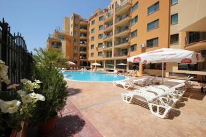 uma piscina com cadeiras e guarda-sóis ao lado de um edifício em Menada Amadeus 3 Apartment em Sunny Beach