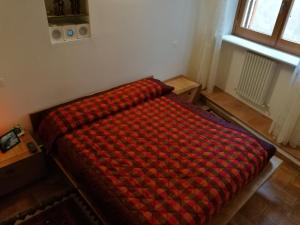 a bed in a room with a red blanket on it at Il nido della rondine, appartamento nel borgo medievale in Cartoceto