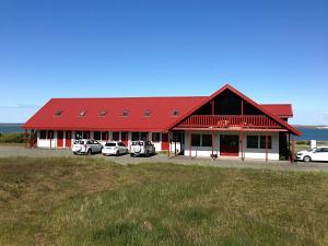 um celeiro vermelho com carros estacionados em frente dele em Hotel Hafnarfjall em Borgarnes