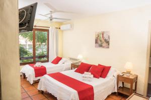 a bedroom with two beds with red and white sheets at Viajero Posada B&B in Colonia del Sacramento