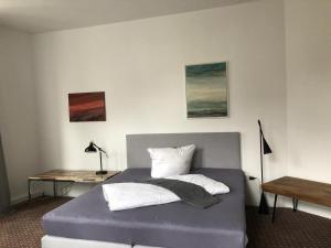 1 Schlafzimmer mit einem Bett mit einem Schreibtisch und 2 Kissen in der Unterkunft Schillers Hotel & Café - GARNI - in Lüdenscheid