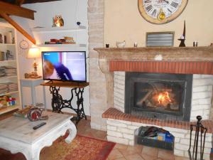 sala de estar con chimenea y TV en La Maison de Sennevoy, en Sennevoy-le-Bas