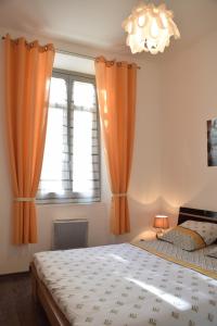 um quarto com 2 camas com cortinas cor de laranja e um lustre em Coeur de Cannes - 5mn Croisette Palais - Terrasse et Parking em Cannes