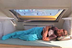 Um homem deitado numa cama numa caravana. em Sandbank2go em Cuxhaven