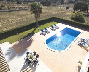 een uitzicht over een zwembad met stoelen en een palmboom bij Villa Sardenha by Algarve Vacation in Guia