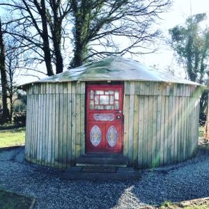 a smallshed with a red door in a yard at McClure Yurt at Carrigeen Glamping in Kilkenny