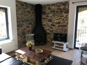 sala de estar con pared de piedra y estufa de leña en Torre de la Ferrería, en Tona