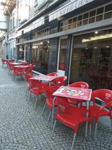 a row of red tables and chairs in front of a store at Residencial Real - Antiga Rosas in Vila Real